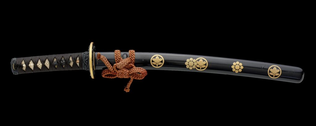Golden and black samurai sword of the type wakizashi as koshirae with a decorative family crest (kamon) of the Ii clan and the Kikkawa Clan with the signature of Omori Teruhide.