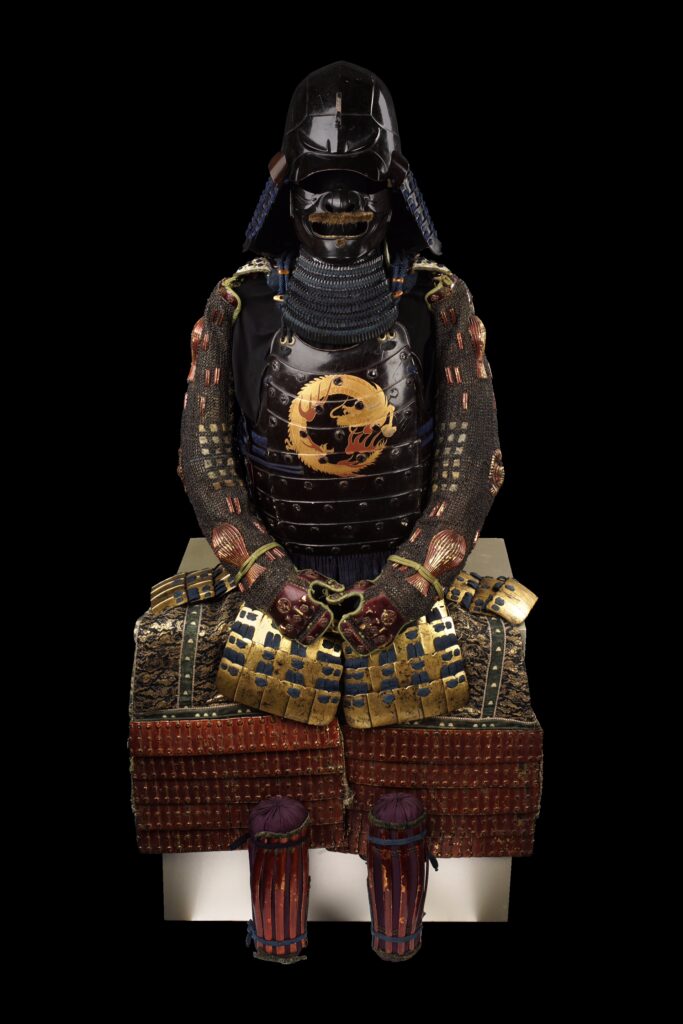 Black-lacquered samurai armor formerly belonging to Honda Masashige (1580–1647), featuring a decorated cuirass, helmet, face mask, arm guards, thigh guards, and shin guards, with dark-blue lacing and gold ornamentation.