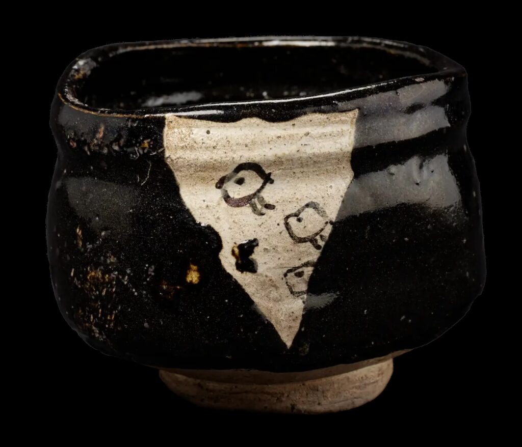 Black Oribe tea bowl (chawan) from the Momoyama period (1573–1615), decorated with stylised chidori birds and an unglazed triangular window revealing the natural Mino clay. From the collection of Samurai Museum Berlin.