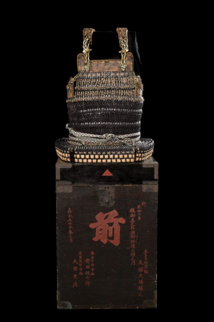 Japanische Haramaki-Rüstung aus der späten Muromachi-Zeit mit schwarz lackierten Eisenplättchen, Hüftschutz aus Rohhaut und dekorativer Lederschnürung mit weißen Kirschblütenmotiven.