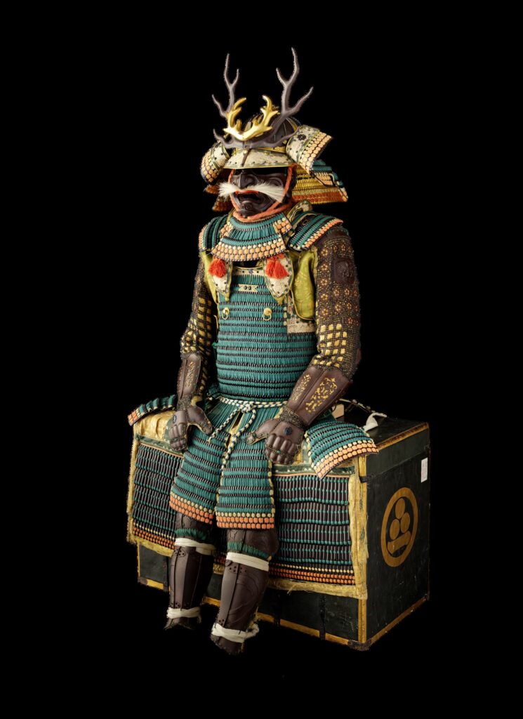 Japanische Tachi-dō-Rüstung mit türkisfarbener Schnürung, einem kunstvoll verzierten Helm und golddekorierten Armschützern.