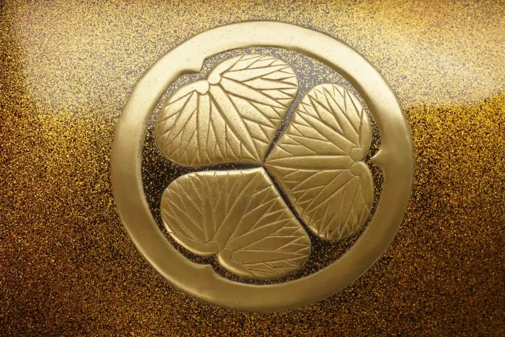 Close-up of the golden Tokugawa mitsuba-aoi crest on black nashiji lacquer