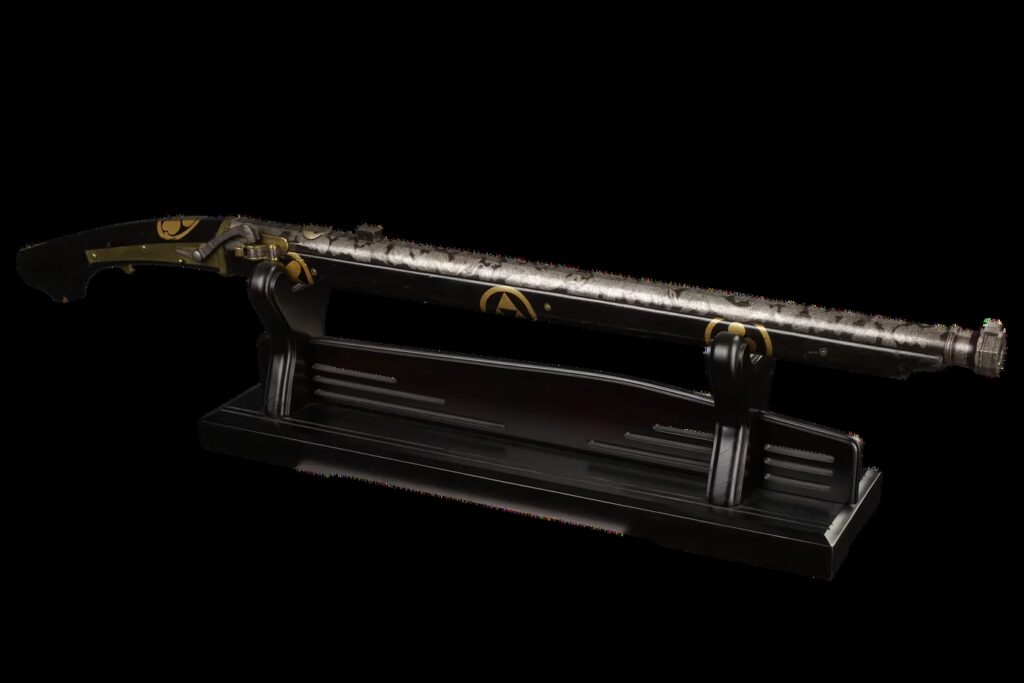 Decorated Japanese matchlock gun (tanegashima) from the Edo period, with a black lacquered stock, gold family crests, and a barrel decorated with inlaid dragons, clouds, and ornamental bands.